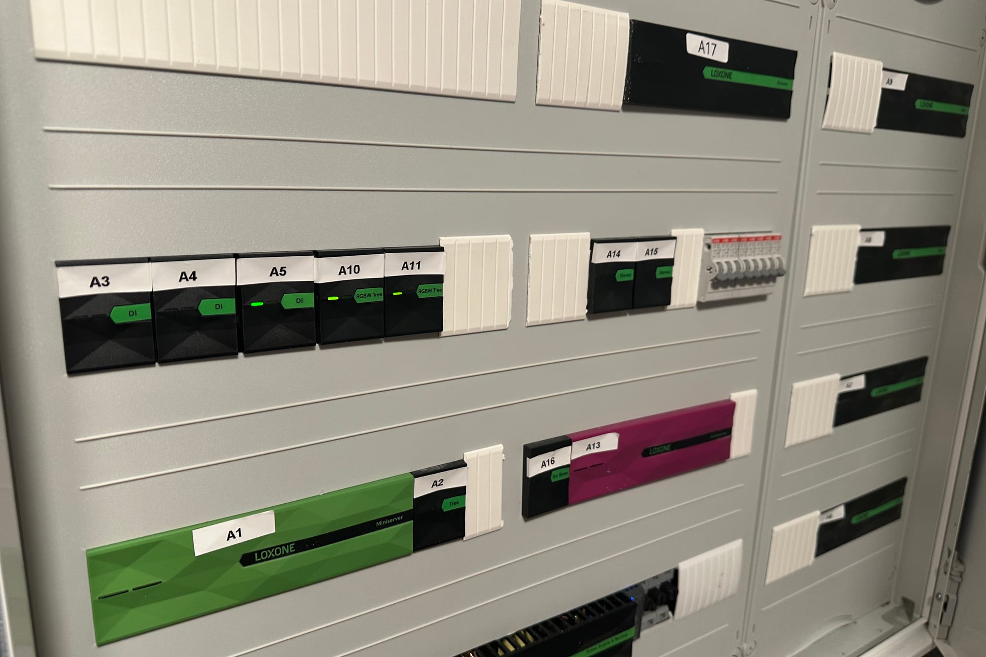 Geöffneter Loxone-Schaltschrank mit grünem Miniserver und beschrifteten Tree-Modulen